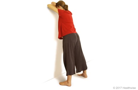 Person leaning forward against a wall.