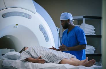A technician prepares to slide a patient into an MRI machine.