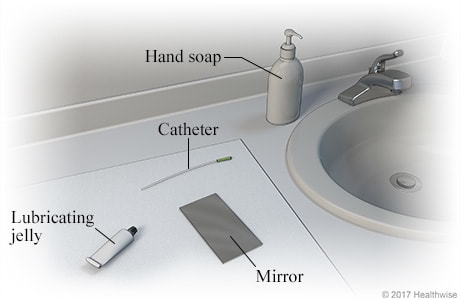 Bathroom sink area, showing supplies of hand soap, catheter, lubricating jelly, and mirror on clean cloth.