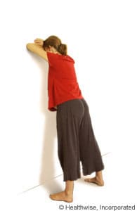 Person leaning forward against a wall.