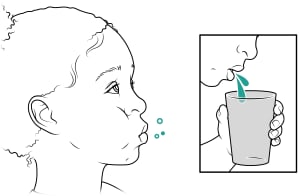 El niño se enjuaga la boca y escupe en la taza.