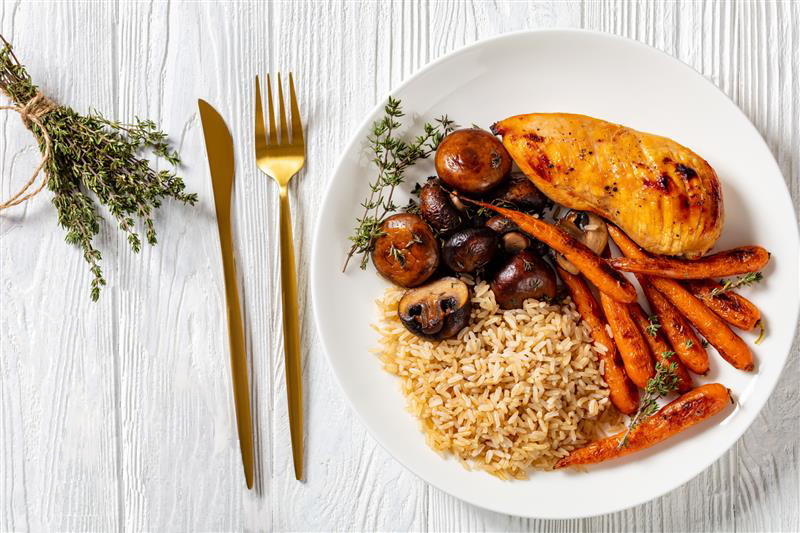 Plate with chicken breast, carrots, mushrooms, and rice.